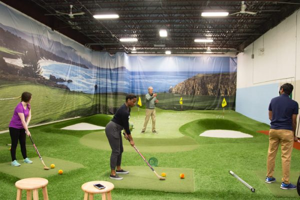 Adult golfer analyzing TrackMan data at an indoor golf training session aimed at lowering his handicap.