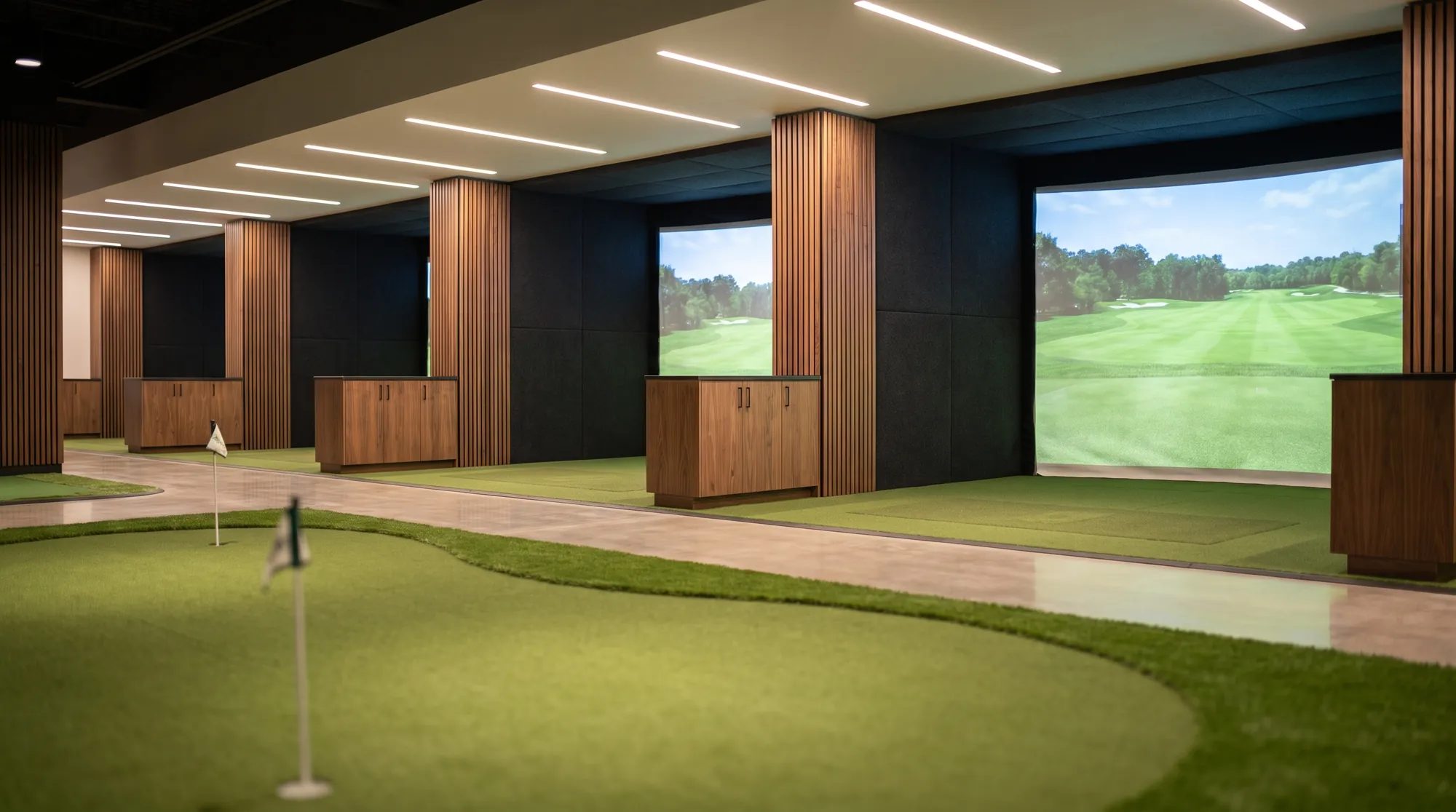 Indoor golf training facility with Trackman simulator bays and a putting green